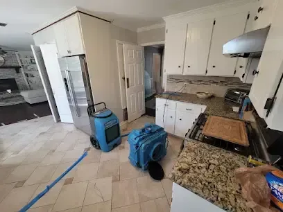 Dehumidifier and air mover running in a kitchen after a leak