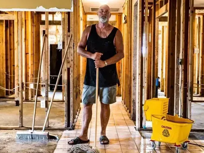 Hallway opened to the studs while a homeowner mops up after a flood