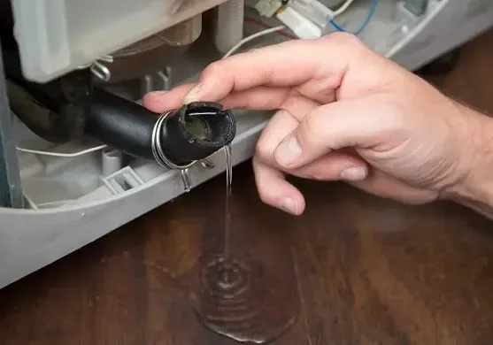 Failed washing machine hose dripping water in a laundry area