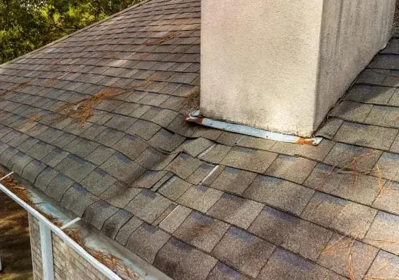 Weathered asphalt shingles and chimney flashing on a residential roof