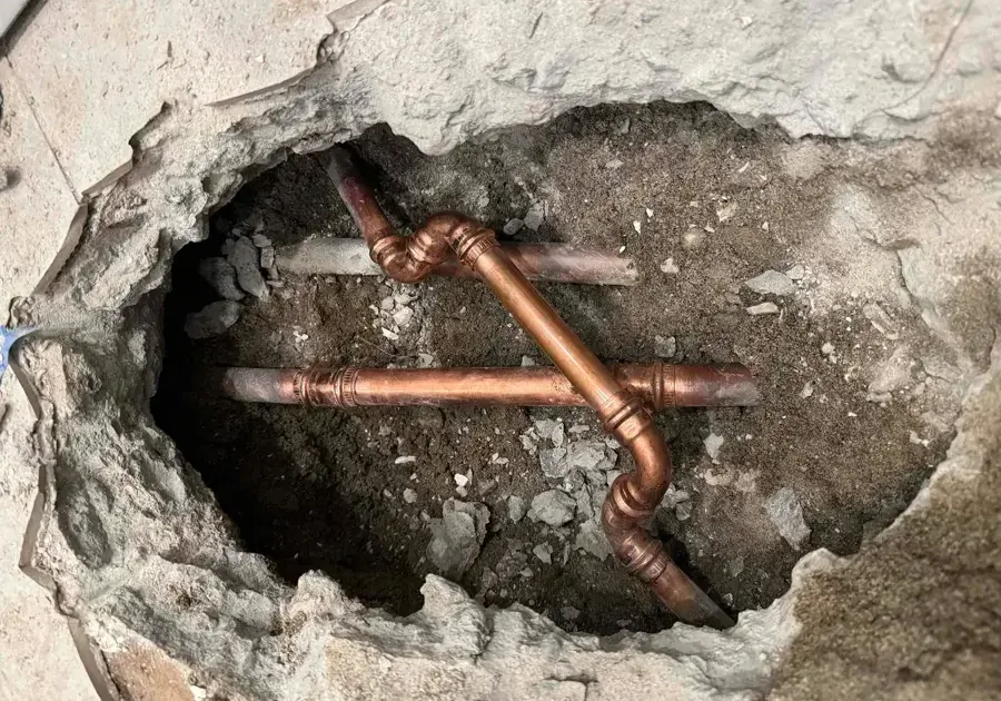 Copper supply lines showing through an opening cut into a concrete slab floor